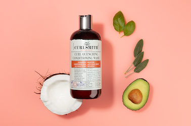 a bottle of shampoo next to avocado and leaves