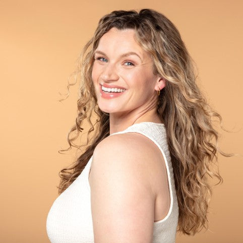 Smiling woman with beautiful, healthy wavy blonde hair, styled effortlessly to showcase natural texture and shine. Perfect representation of radiant, well-cared-for curls and waves