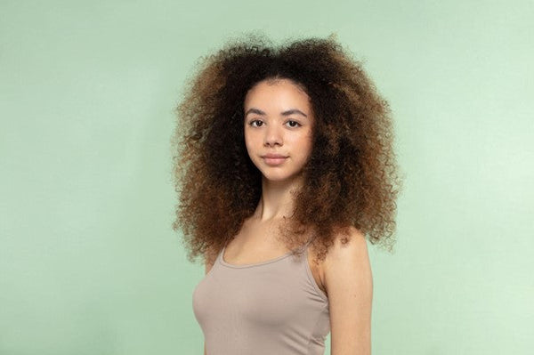 Woman with coily hair on a green background