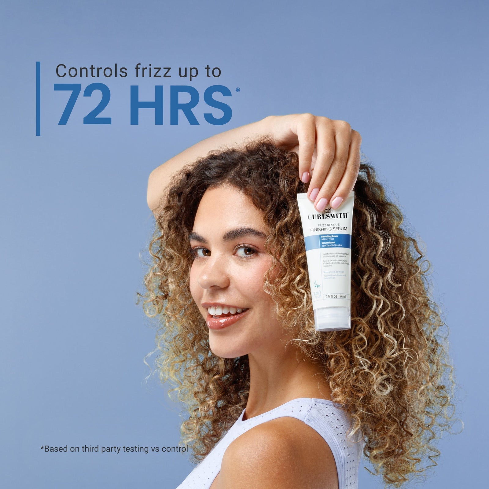 Woman with curly hair holding a bottle of hair product against a blue background, Click to enlarge