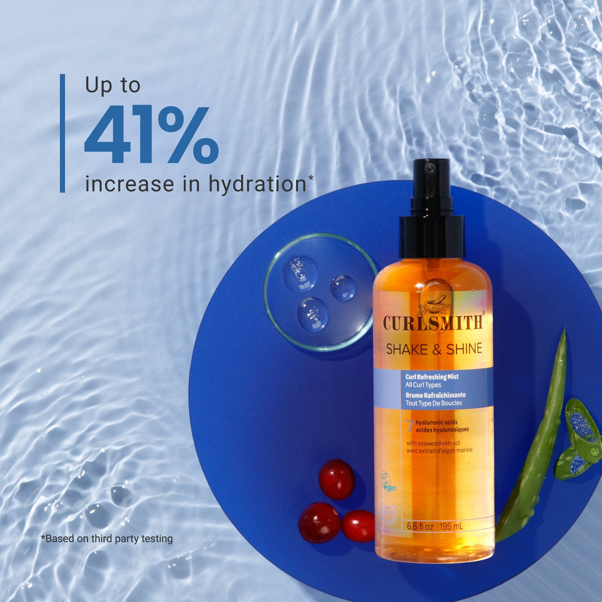 Curlsmith Shake & Shine product on a blue circular mat with water droplets and cherries, against a light blue background.